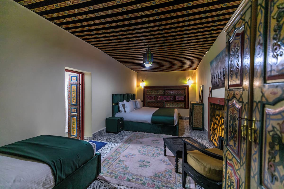 A room with a bed, a sofa, a small table, and a decorative wall.