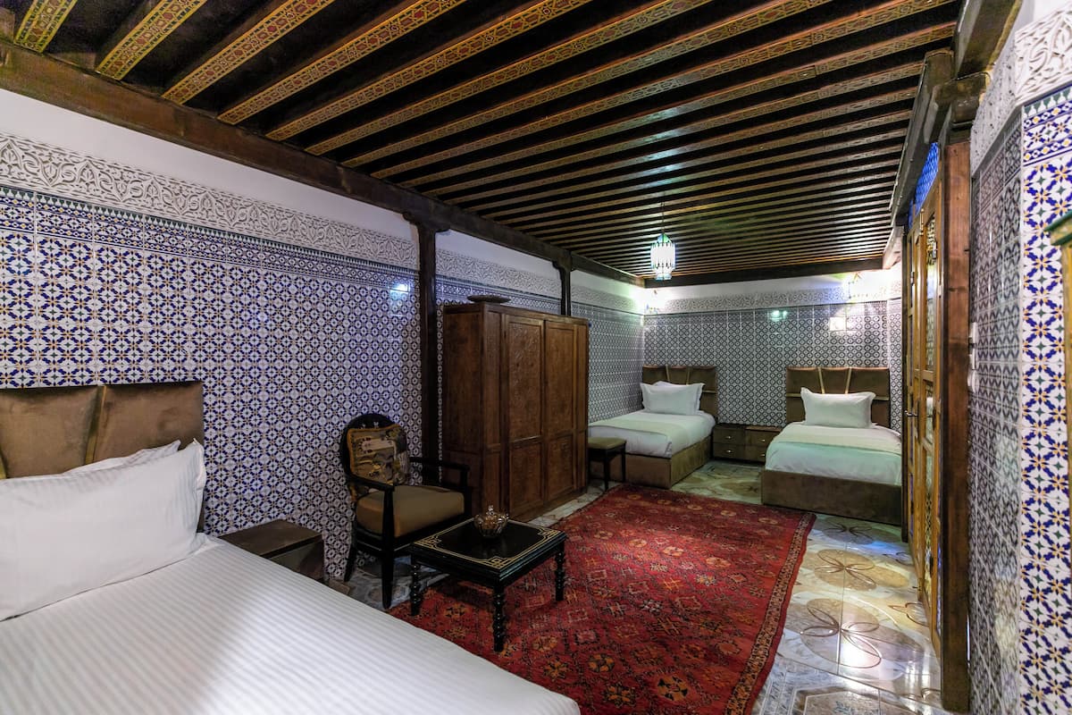 A traditional room with a bed, two sofas, a wooden wardrobe, and a red carpet.