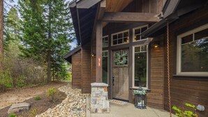 A rustic cabin with a stone entrance, large windows, and a wooden exterior.