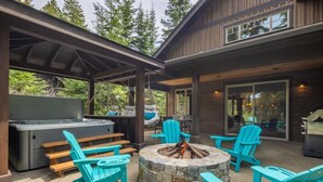 An outdoor patio with a stone fire pit, wooden benches, and turquoise Adirondack chairs.