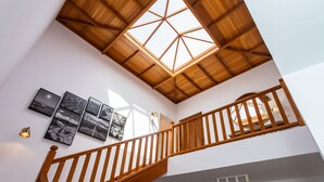 A wooden staircase with a skylight, white walls, and black-and-white photographs.