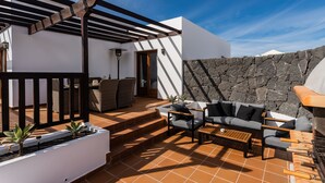 A patio with outdoor furniture, a stone wall, and a pergola structure.