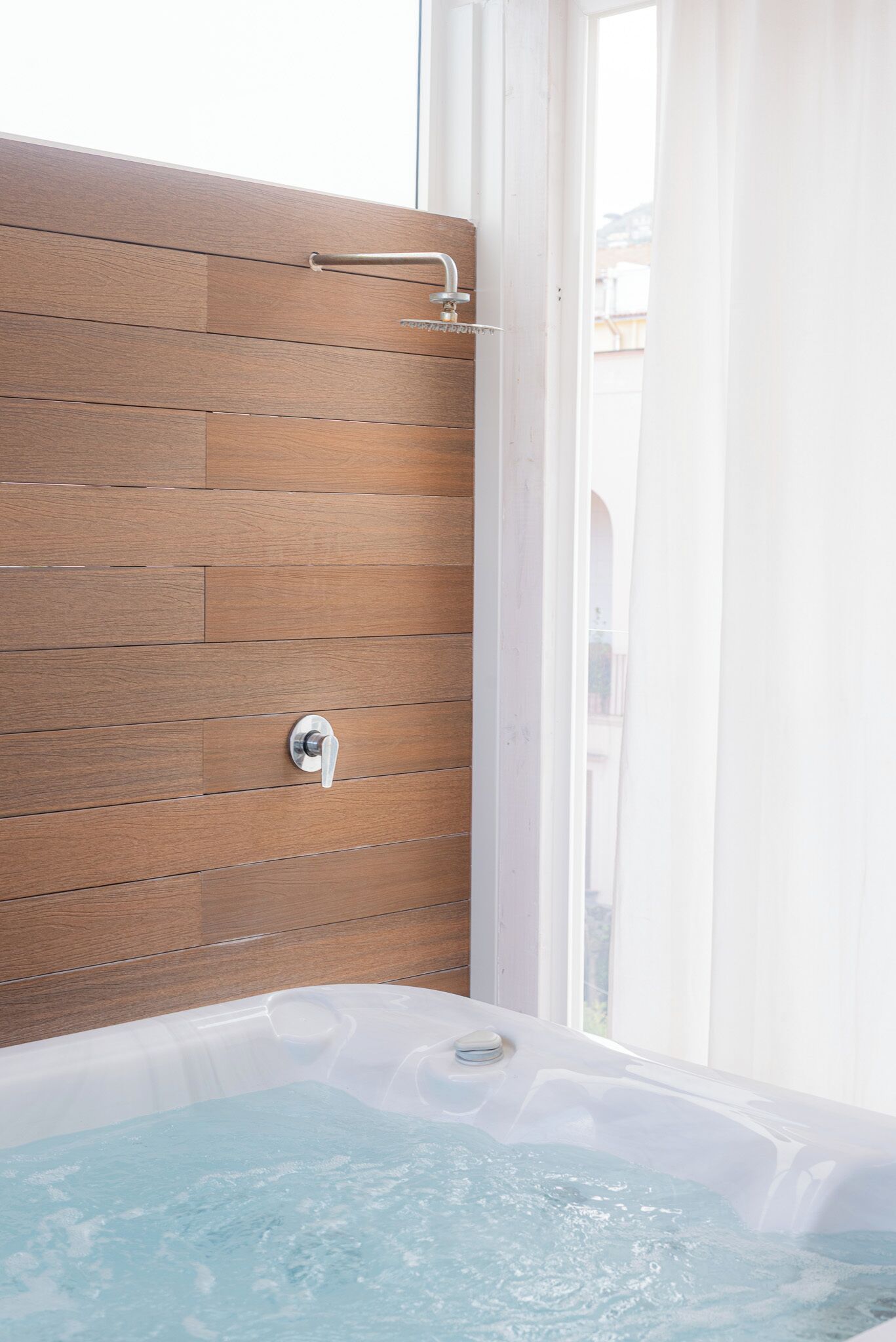 Une salle de bain avec un mur en bois, une pomme de douche et une baignoire remplie d’eau.