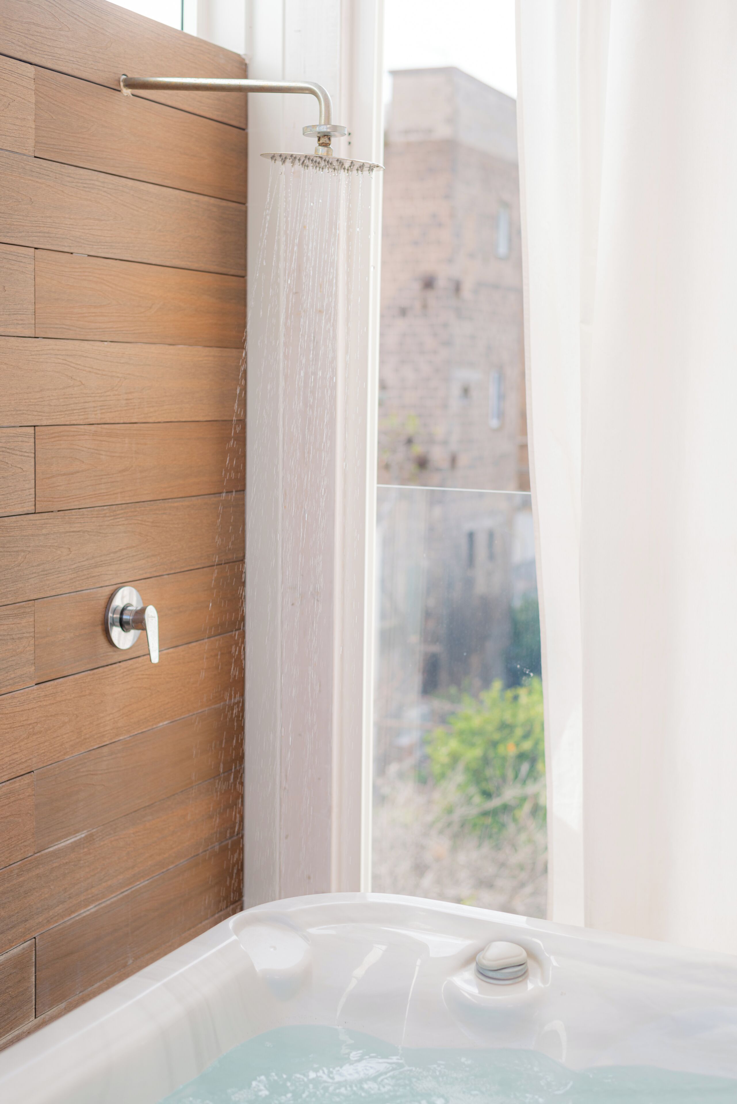 Une salle de bain avec un mur en bois, une pomme de douche et une baignoire.