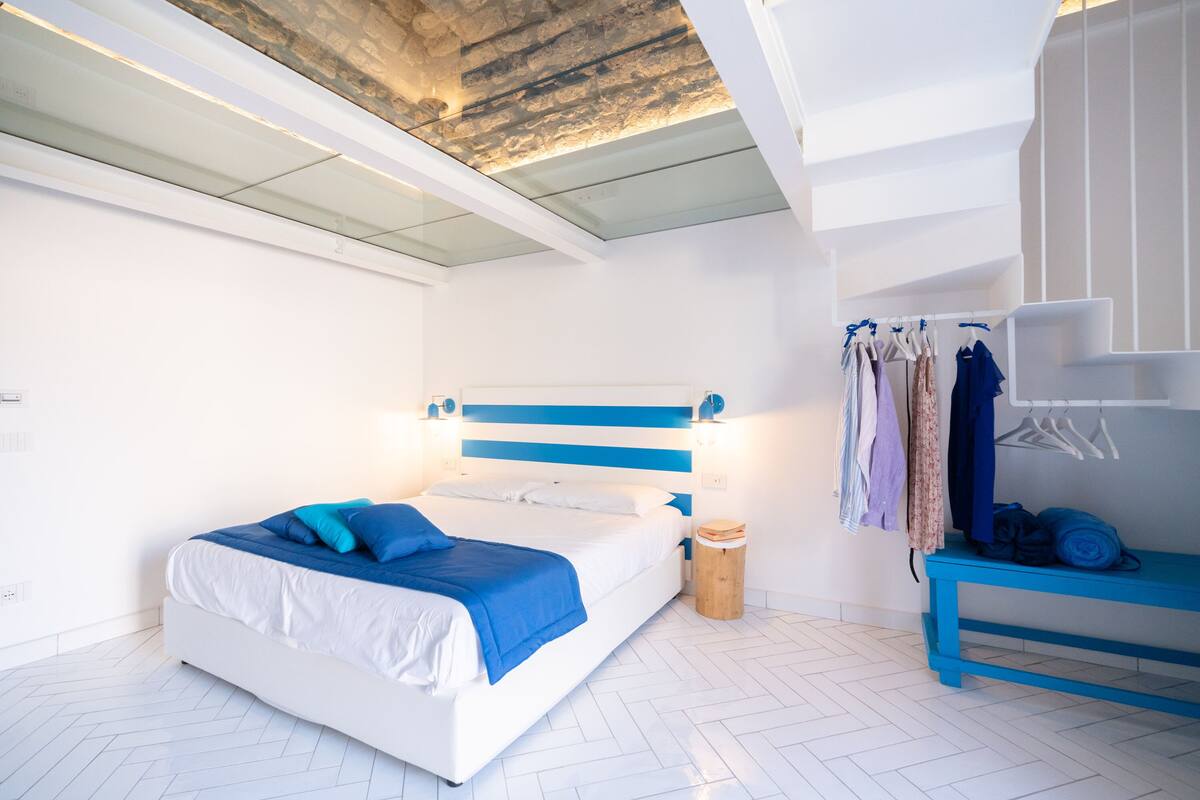 A modern bedroom with a bed, bedside table, and a clothing rack.