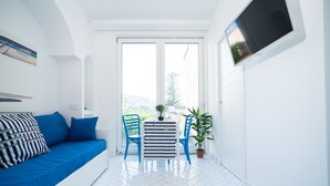 Et lyst, hvidt rum med en blå sofa, et stribet bord og to blå stole.