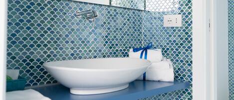 A bathroom with a white sink, blue tiled walls, and a towel rack with towels.