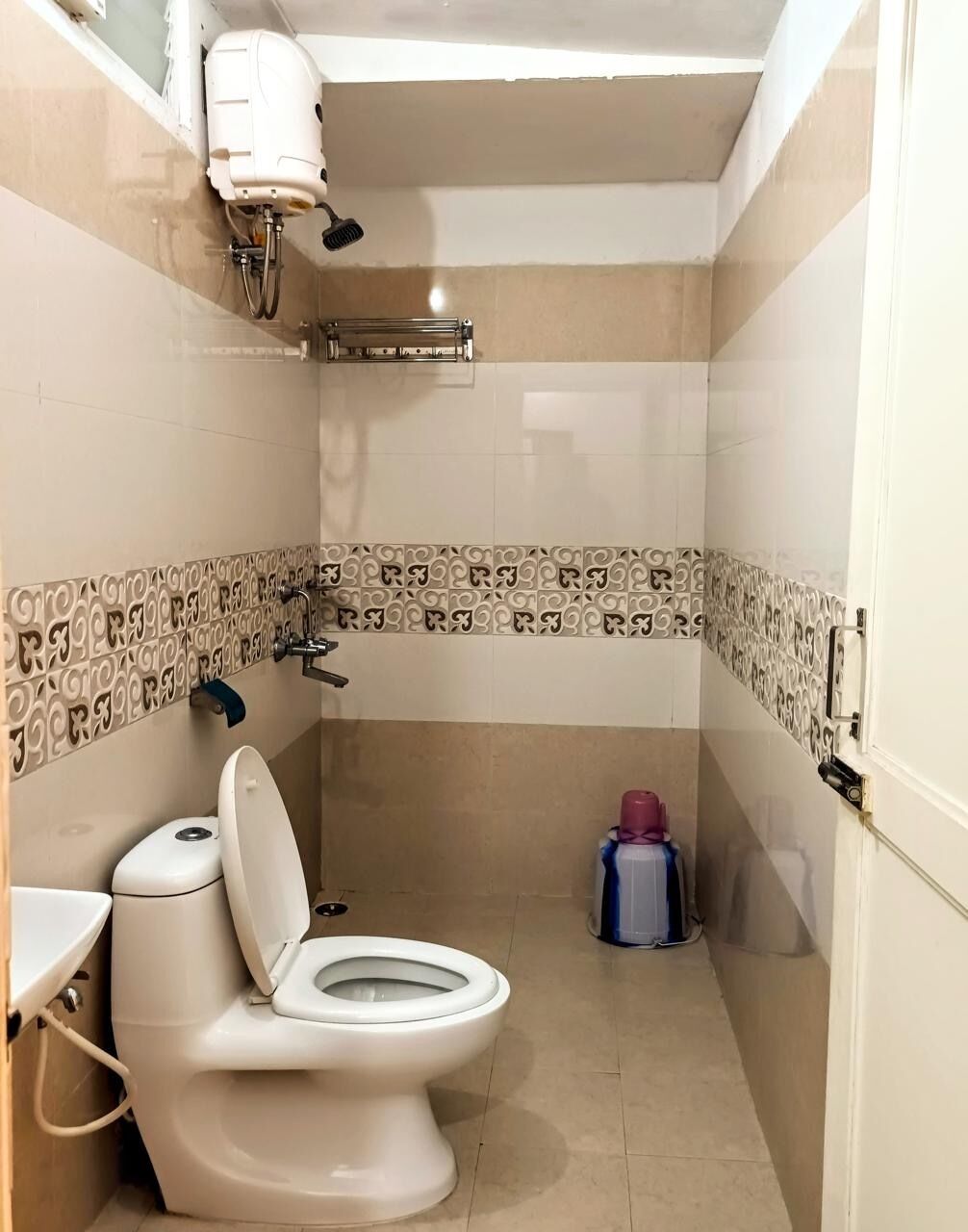 Um banheiro pequeno com vaso sanitário, secador de mãos e lixeira.