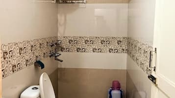 Um banheiro pequeno com vaso sanitário, secador de mãos e lixeira.