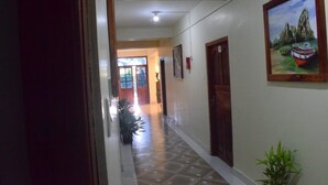 A hallway with a tiled floor, wooden doors, and a framed painting on the wall. - Aashrey Bed and Breakfast (Port Blair)