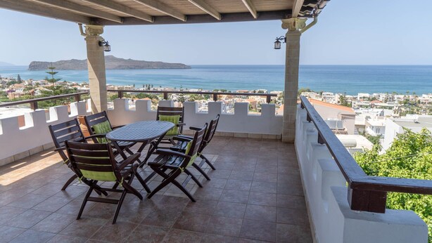 A covered terrace with a table and chairs, overlooking a coastal town and the sea. - villa Gregory (Chania)
