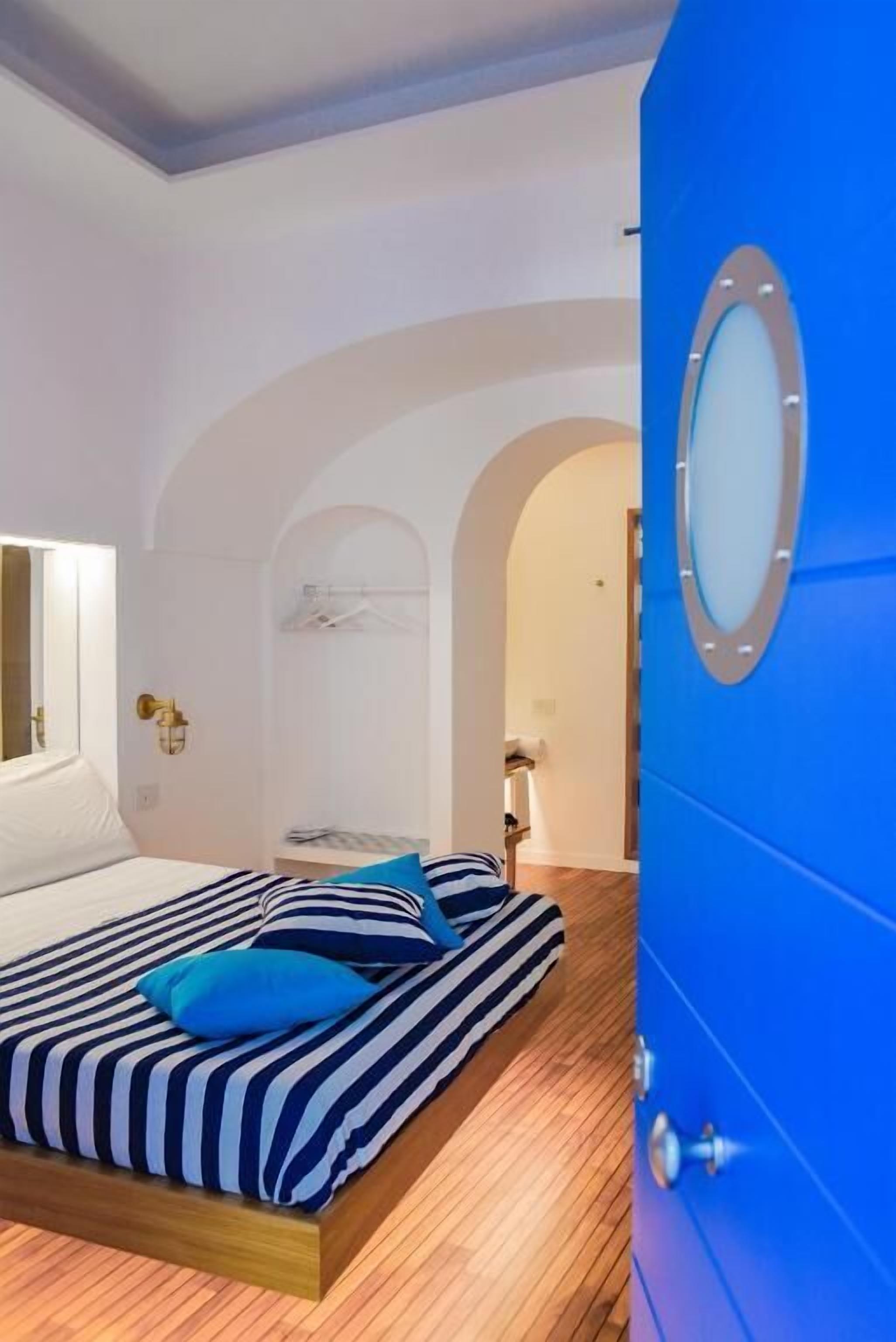 A bedroom with a bed, a blue door, and an arched doorway.