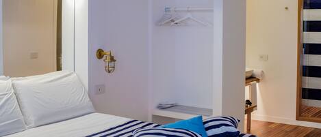 Un dormitorio moderno con piso de madera, una cama con ropa de cama a rayas y una lámpara de pared.