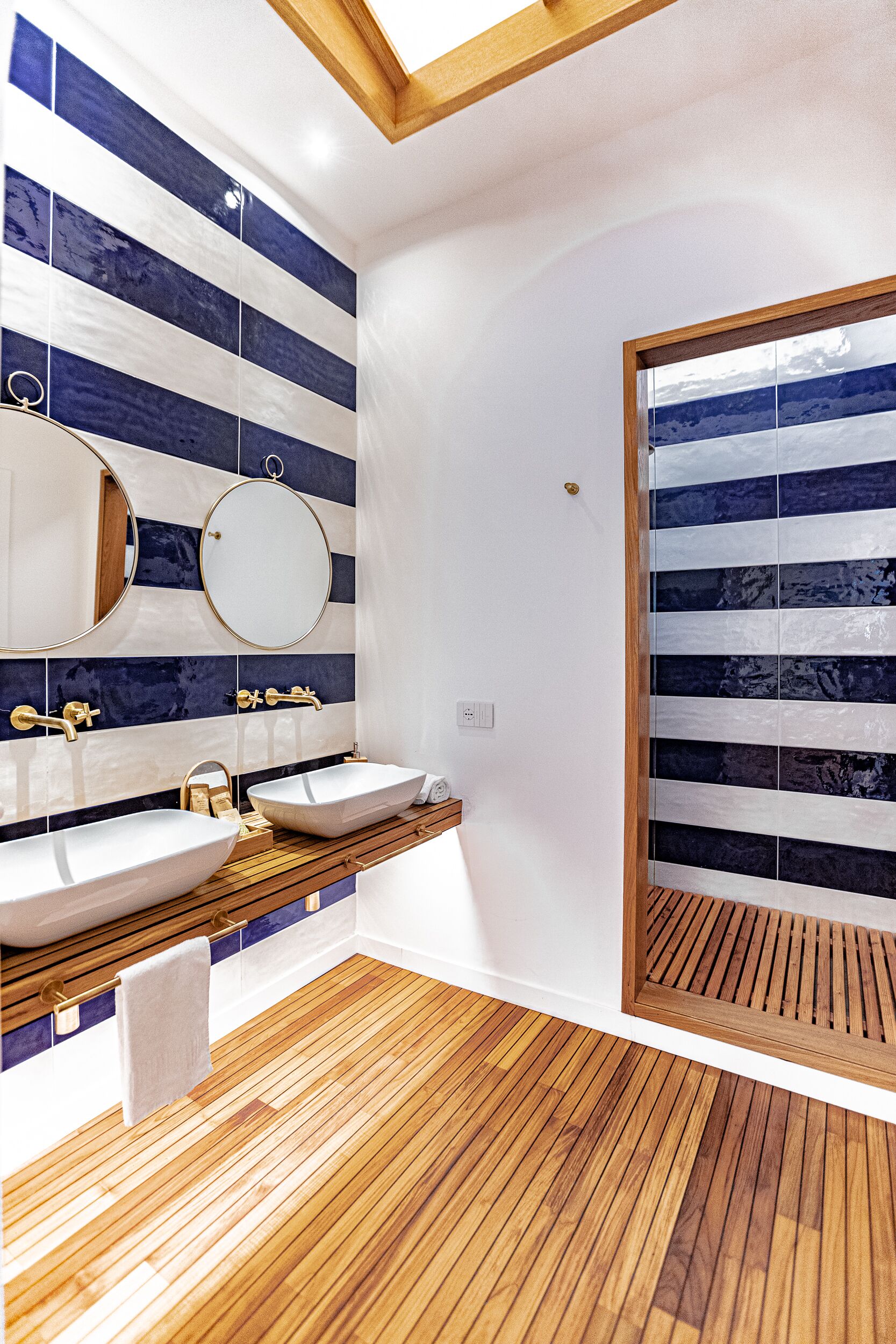 Een moderne badkamer met twee wasbakken, een houten wastafelmeubel en een grote spiegel.