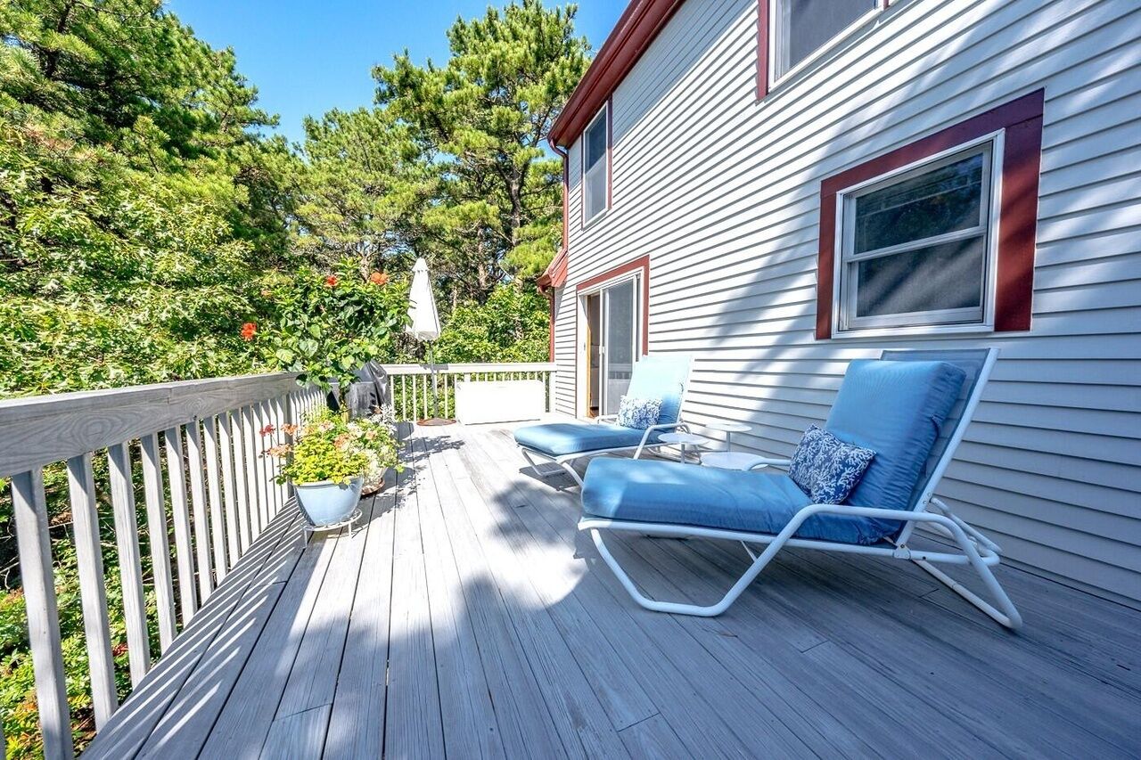 Une terrasse en bois avec deux chaises longues bleues et une plante en pot.