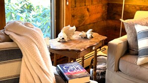 Une pièce chaleureuse avec une table en bois, une lampe et un livre intitulé « Cape Cod » posé sur une chaise.