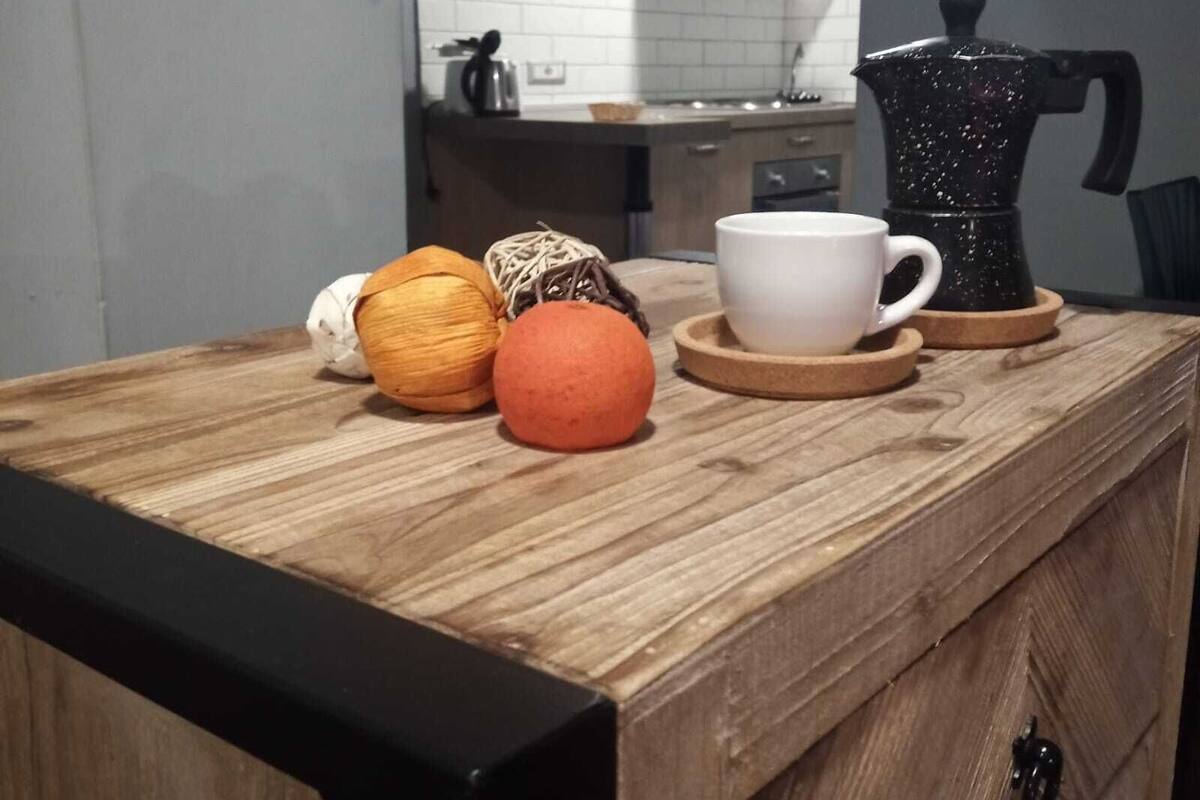 A kitchen counter with a coffee maker, a white mug, and some decorative balls.