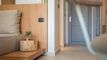 Una sala de estar moderna con suelo de madera, un sofá, una mesita de madera con una planta y una puerta al fondo.