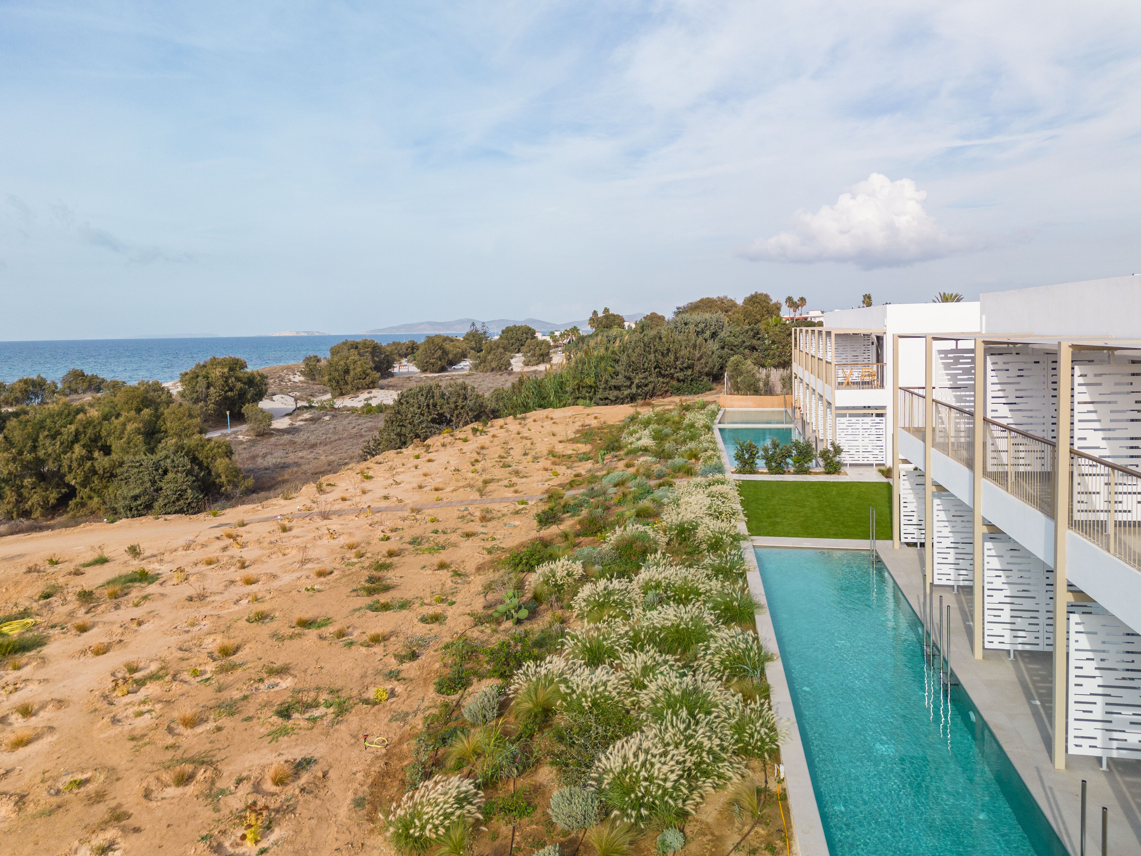 A resort with a pool, a view of the sea, and a desert landscape.