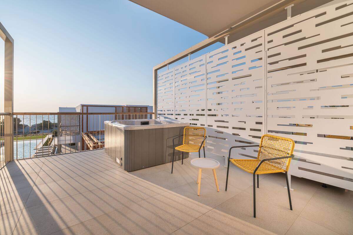 A balcony with a modern design, featuring a bar area with two chairs and a small table.