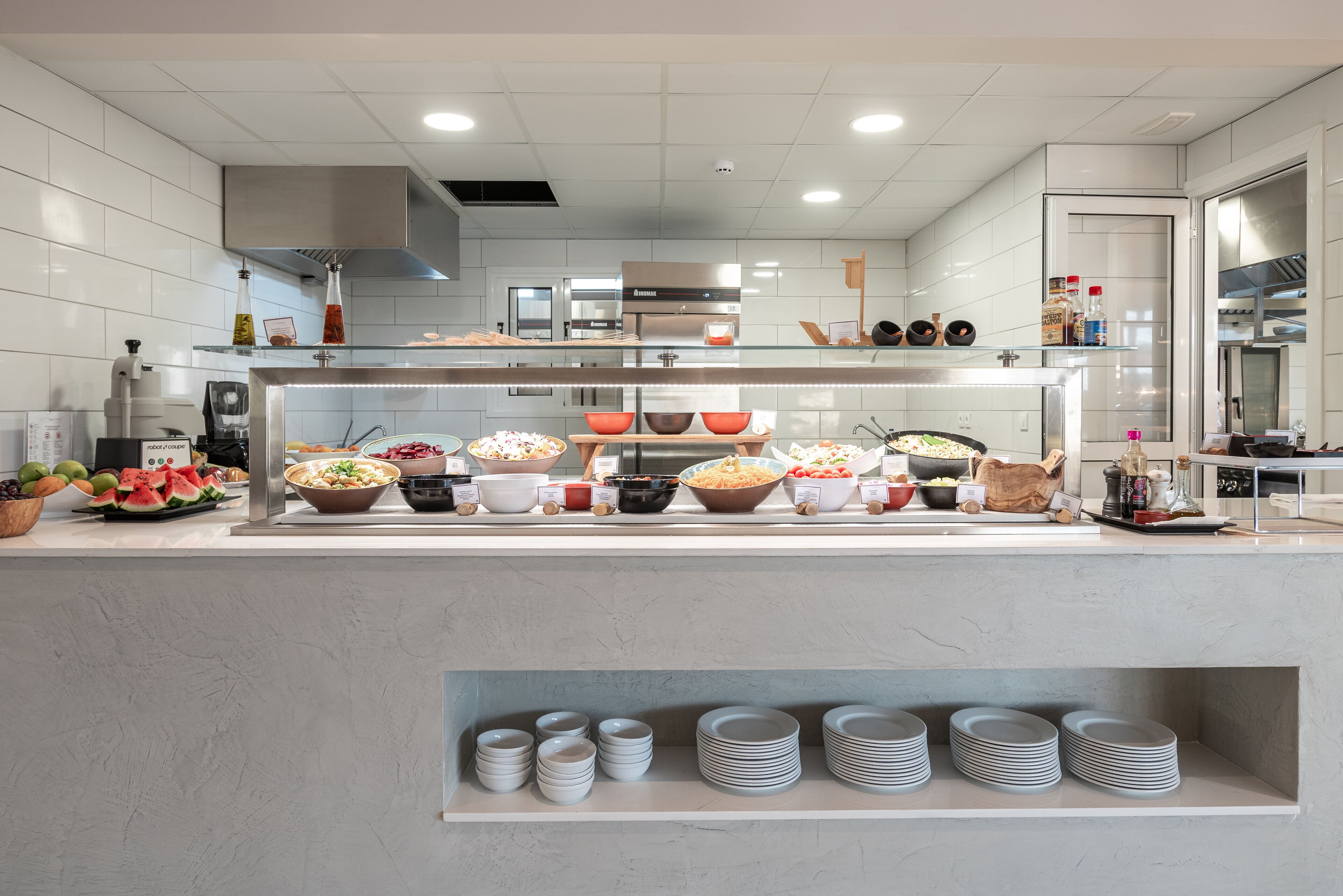 A modern kitchen with a buffet setup, including various food bowls and a glass display case.