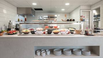 A modern kitchen with a buffet setup, including various food bowls and a glass display case.