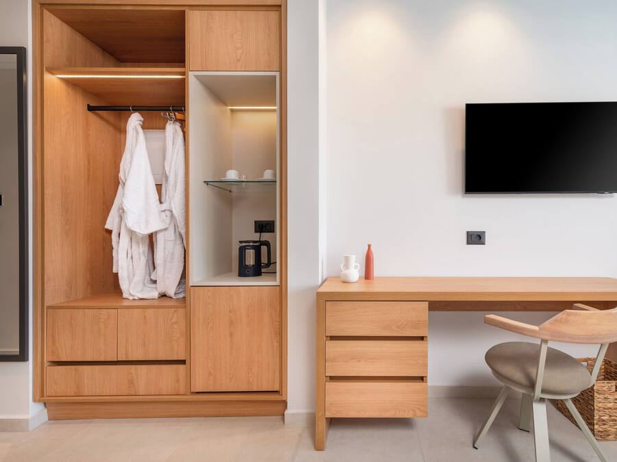 A modern room with a wooden wardrobe, a desk with a chair, and a mounted TV.