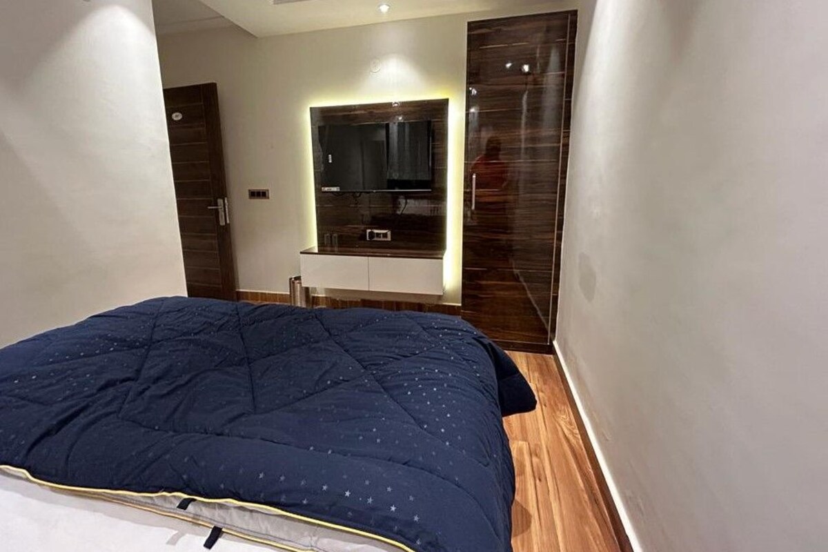 Een moderne slaapkamer met een groot bed, een ingebouwde televisie en een kledingkast.