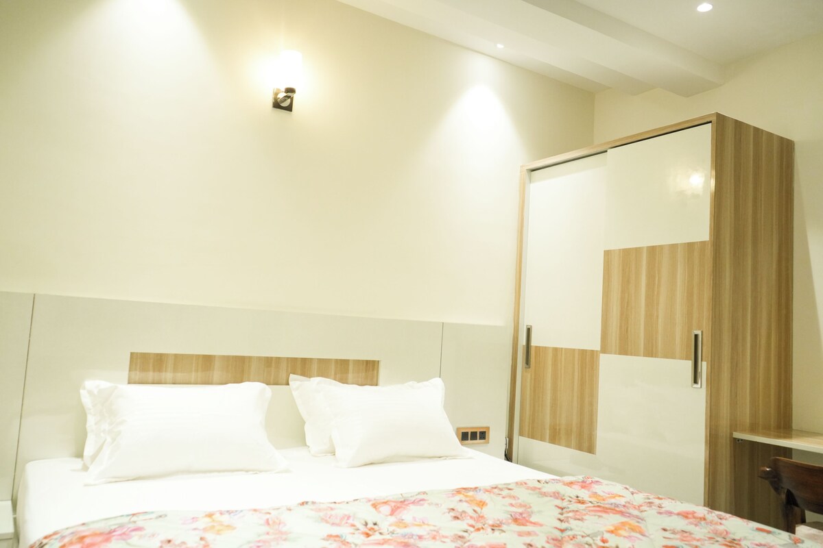 Una habitación de hotel con una cama, un armario de madera y una mesita de noche.