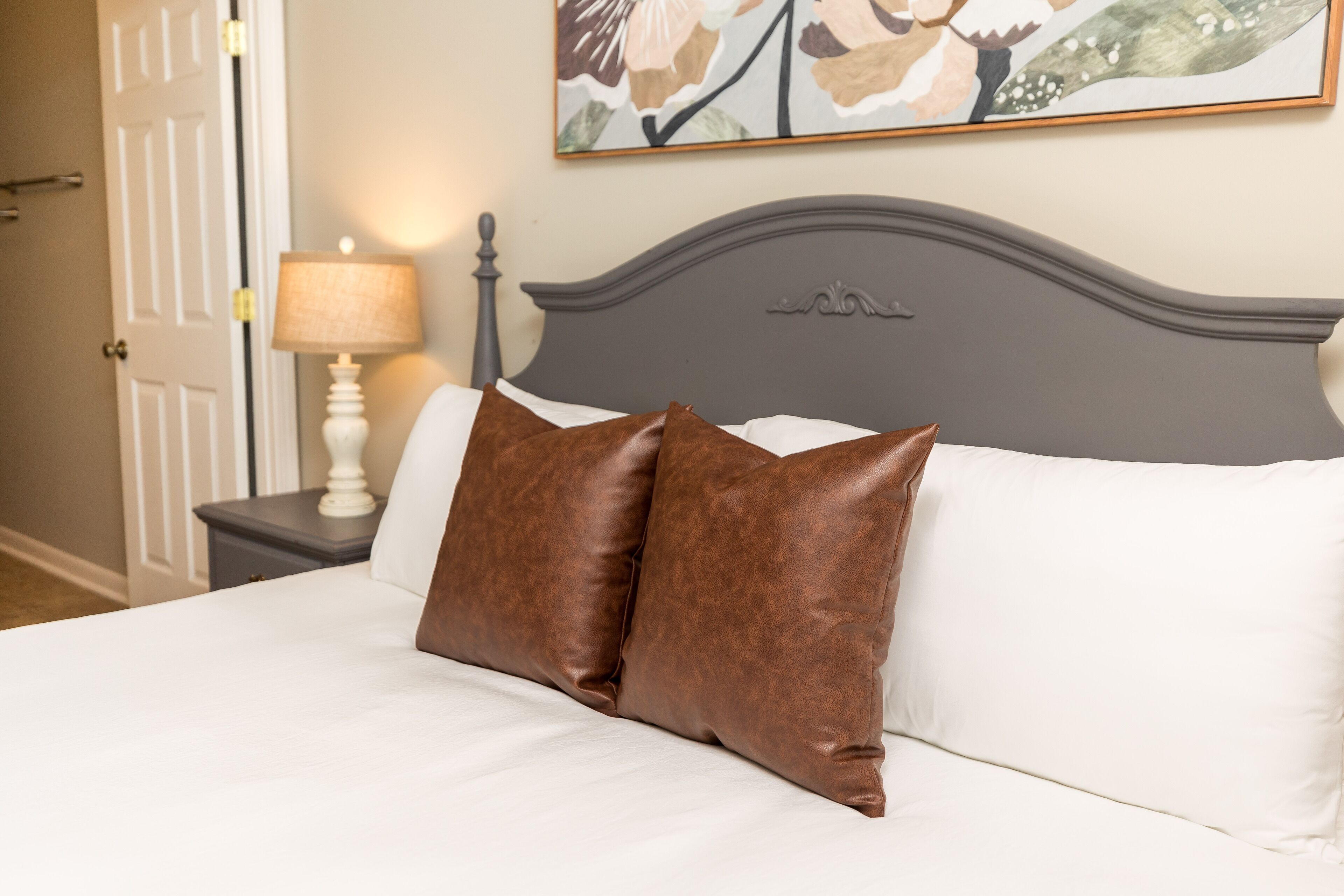 A bed with two brown pillows, a white pillow, and a gray headboard.