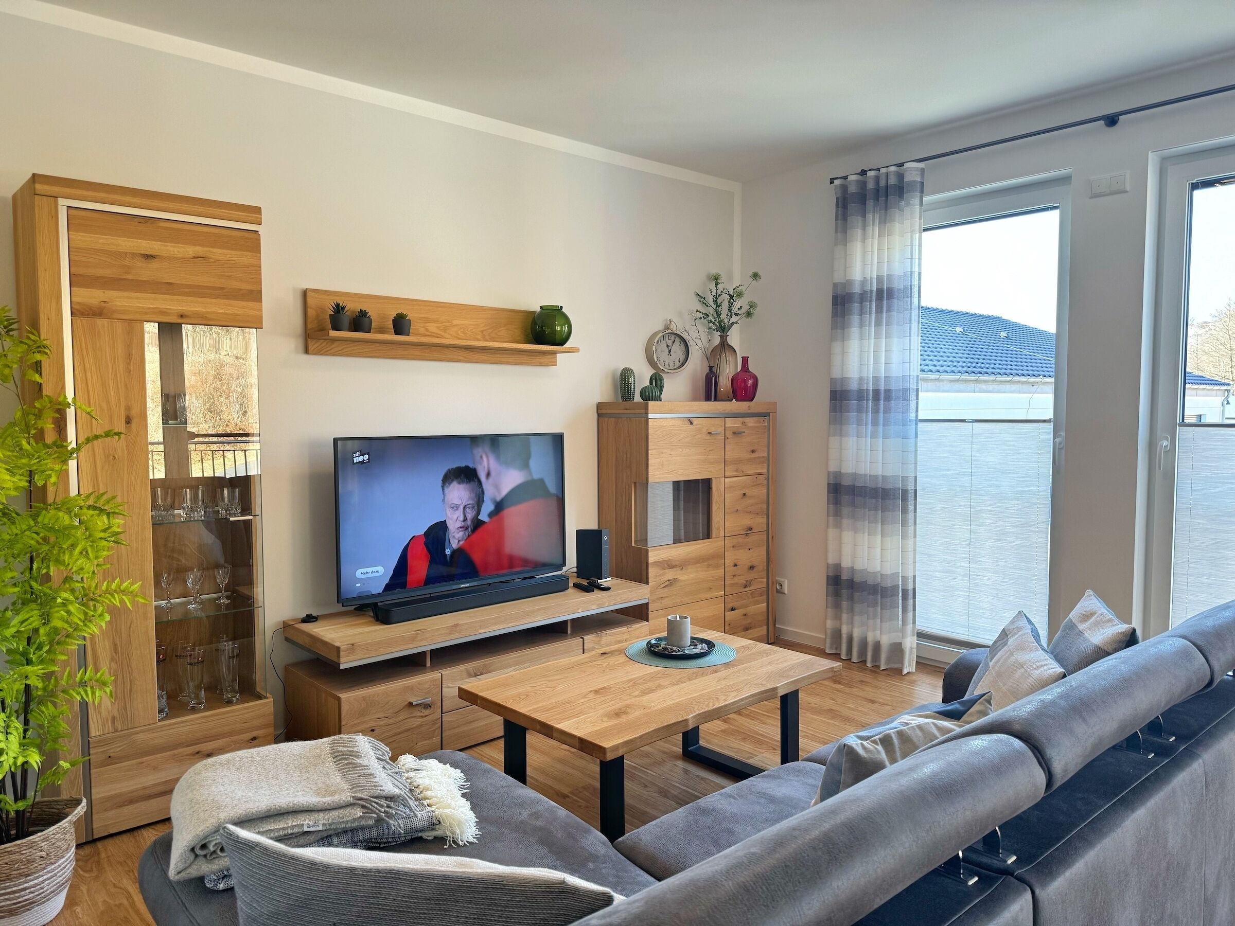 Un salon moderne avec une télévision, des meubles en bois, un canapé et une table à manger.