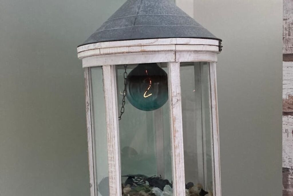 Een witte lantaarn met een glazen omhulsel en een blauwgroen binnenkant.