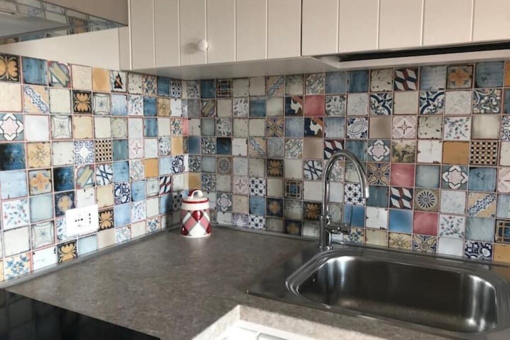 Una cucina con schienale piastrellato e lavello in acciaio inossidabile.