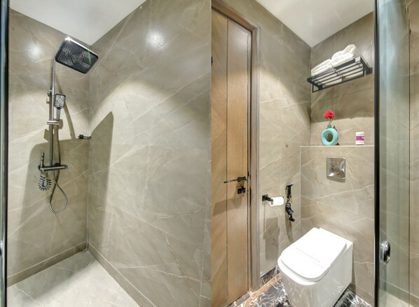 A bathroom with a shower, toilet, and a glass-enclosed shower area.