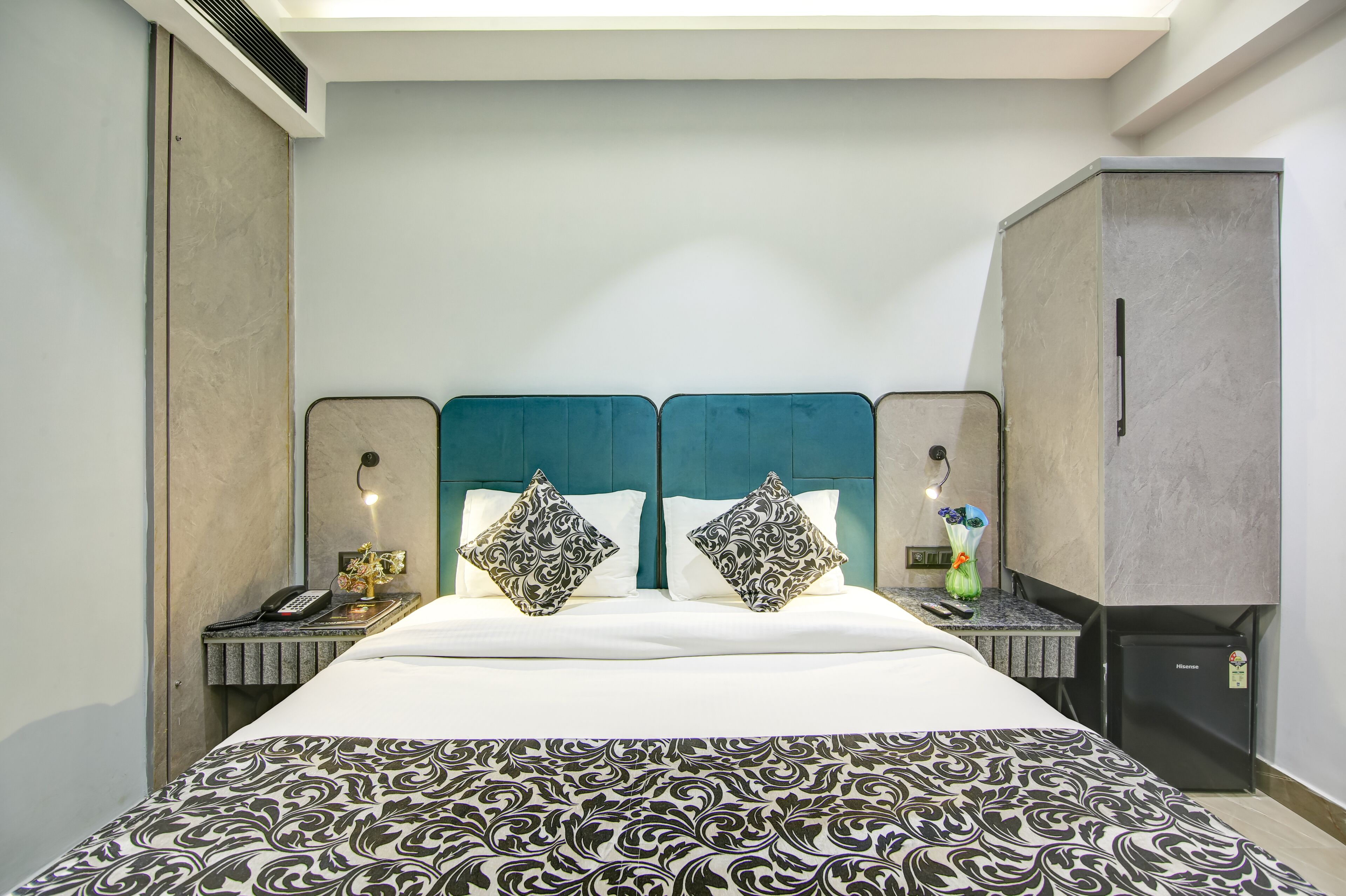Habitación de hotel con una cama grande, dos mesitas de noche, un escritorio y un minibar.
