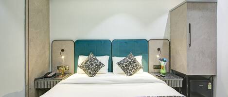 Habitación de hotel con una cama grande, dos mesitas de noche, un escritorio y un minibar.
