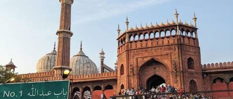 A historic building with domes and minarets, a large gate, and a crowd of people.