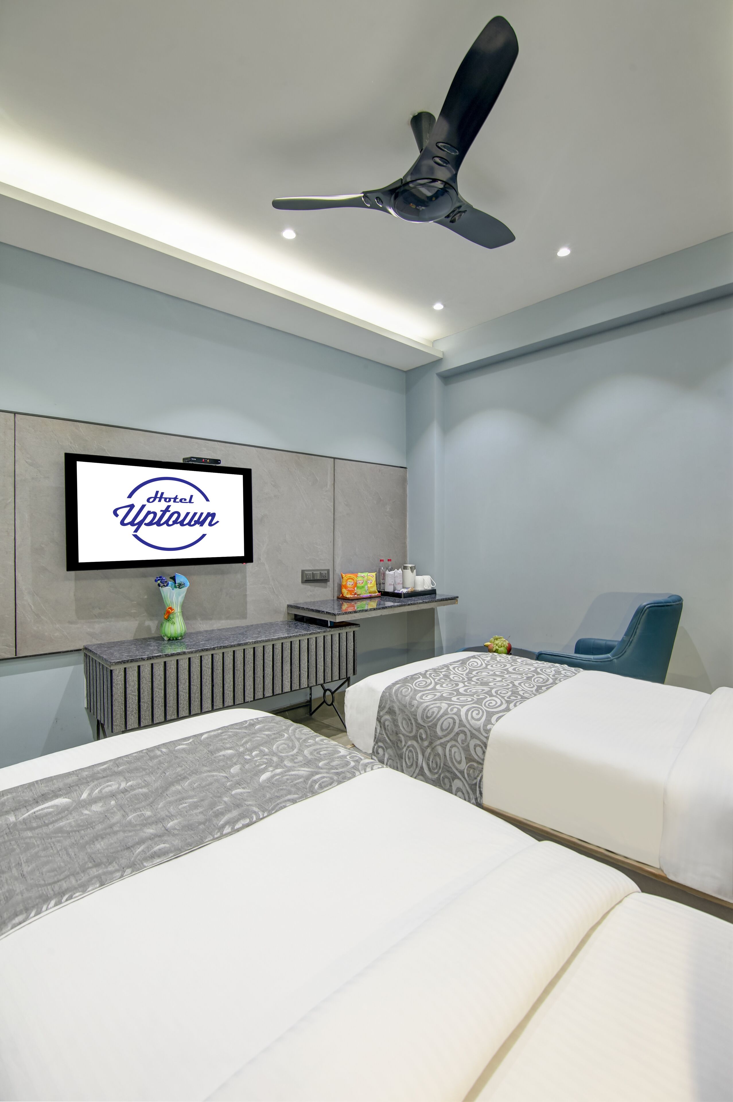 A hotel room with a bed, a desk, a television, and a ceiling fan.