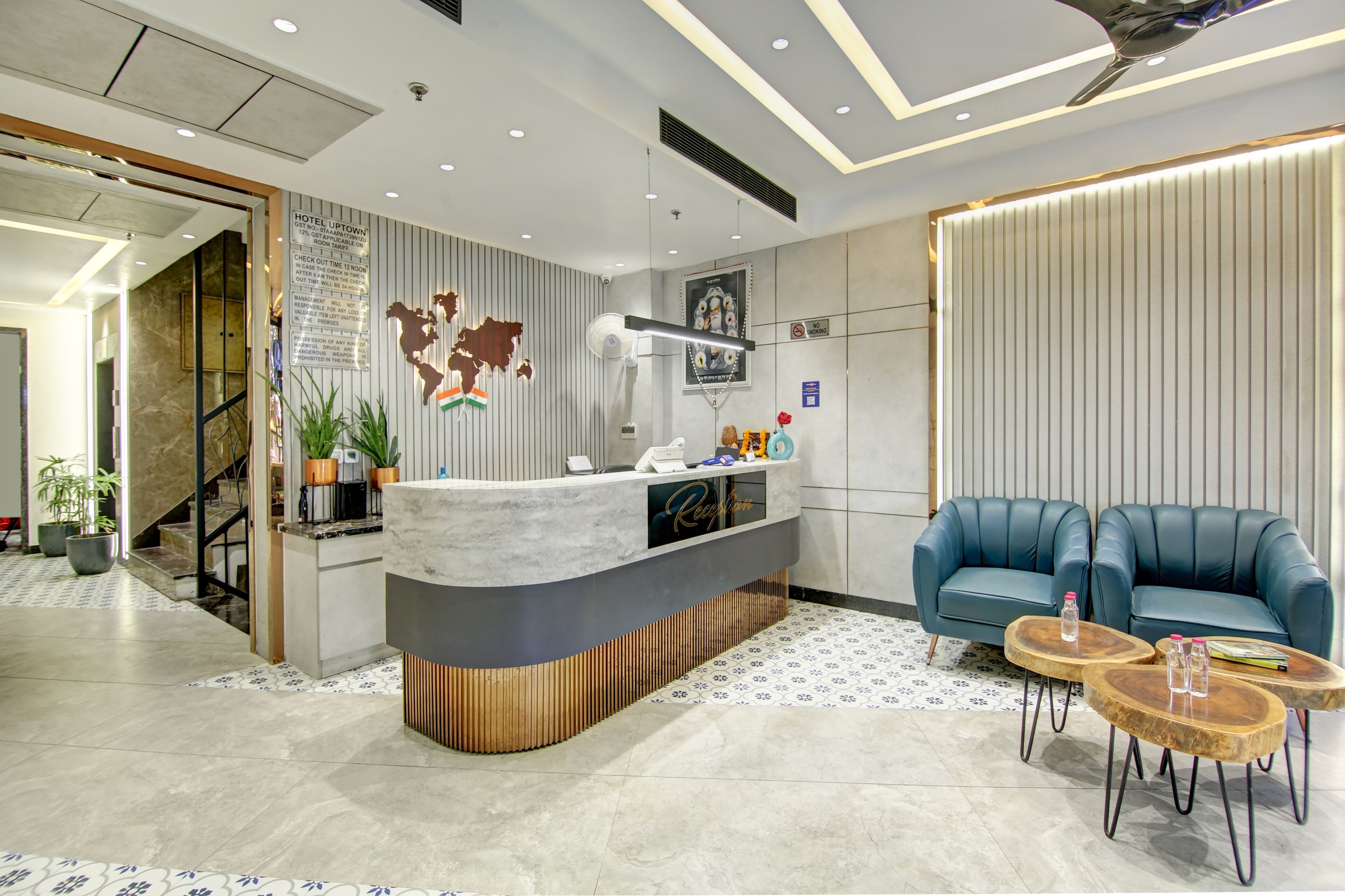 Een moderne hotelreceptie met een marmeren balie, blauwe lederen zitplaatsen en een decoratieve wereldkaart.