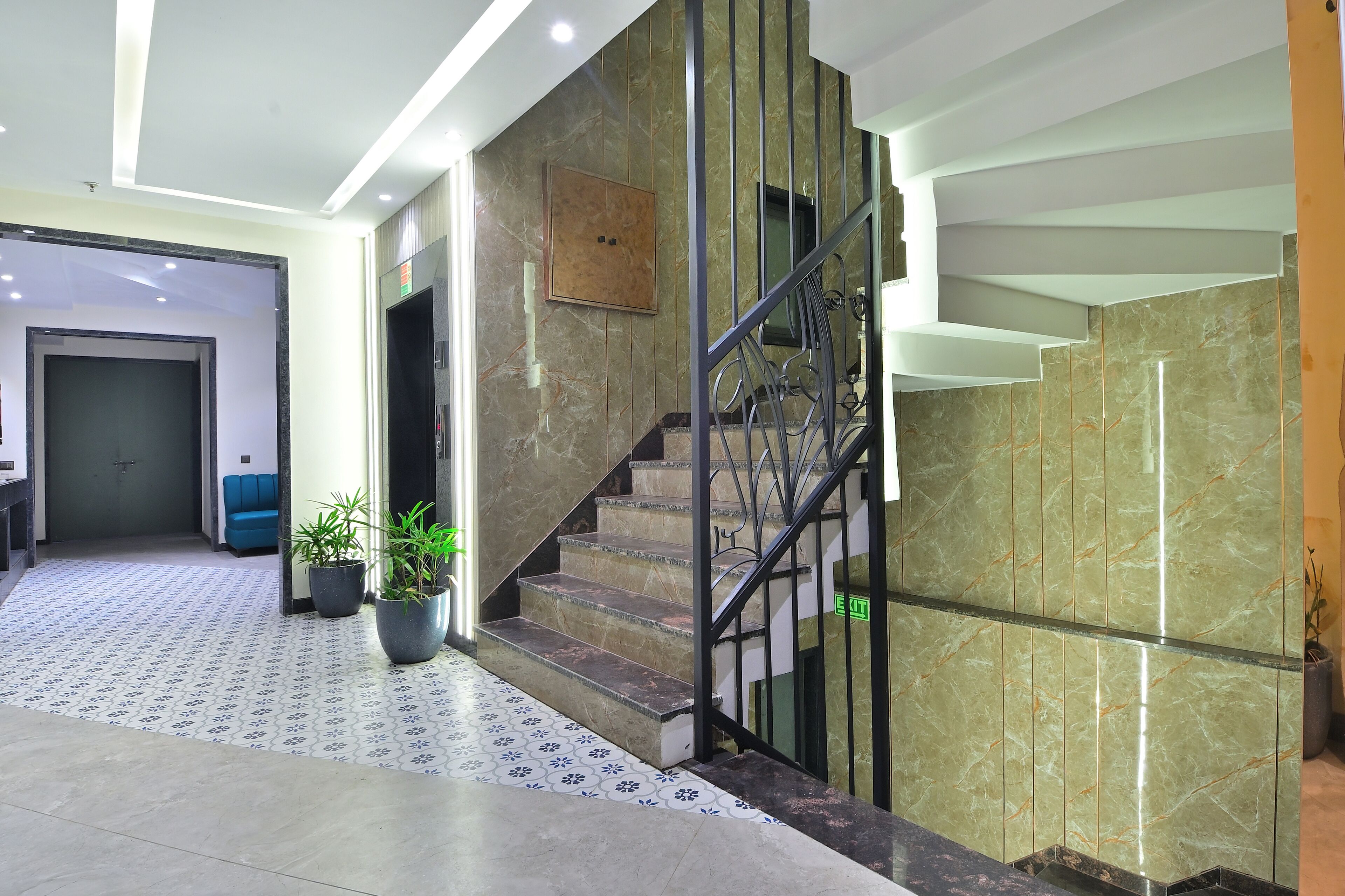 A modern hotel lobby with a marble staircase, potted plants, and a reception area.