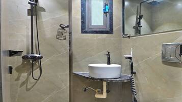 Un bany amb sòl de marbre, un lavabo blanc, un mirall, una dutxa i un vàter.