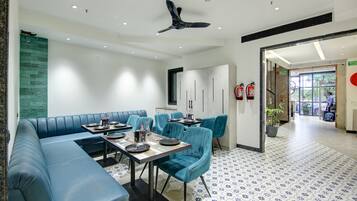 A modern dining area with blue seating, a ceiling fan, and a patterned floor.