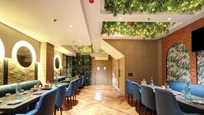 A restaurant with wooden flooring, blue upholstered booths, and a brick wall with a mural. - HOTEL UPTOWN - Luxury Restaurant & Rooftop Near Connaught Place (New Delhi)