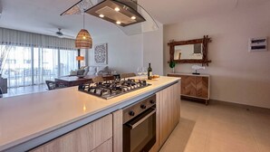 Eine moderne Küche mit einer zentralen Kochinsel, eingebautem Backofen und einem Essbereich inklusive Sofa und Tisch.