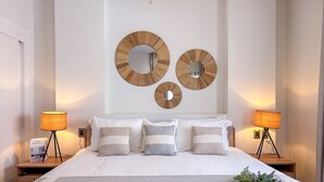 Ein Schlafzimmer mit einem großen Bett, zwei Nachttischen und drei Spiegeln an der Wand.