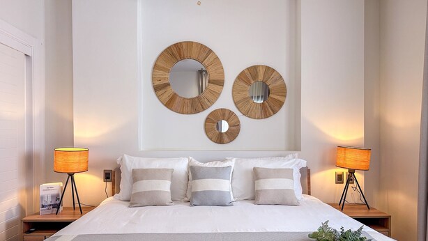 A bedroom with a large bed, two bedside tables, and three wall-mounted mirrors. - Incredibly Beautiful condo just steps to the beach (Punta Cana)