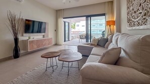 Ein modernes Wohnzimmer mit Flachbildfernseher, Sofa, Couchtisch und dekorativen Wandbildern.