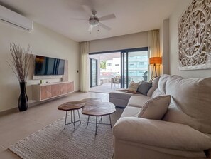 A modern living room with a flat-screen TV, sofa, coffee table, and decorative wall art.