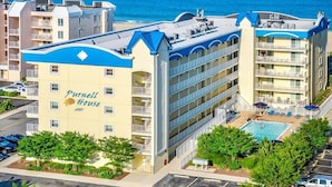 Een hotel met een zwembad, meerdere balkons en uitzicht op de oceaan.