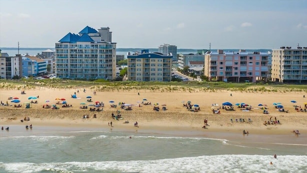 Hotel aan het strand met meerdere gebouwen, een zandstrand en parasols.
